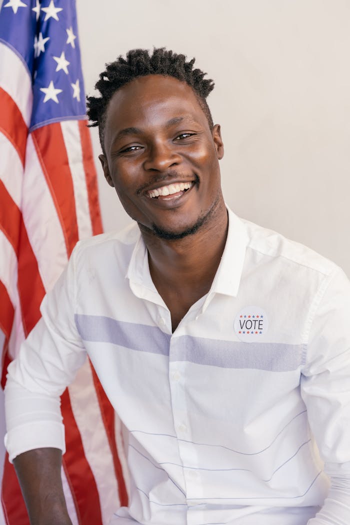 Smiling man with 'I Voted' sticker and US flag, symbolizing democracy and patriotism.